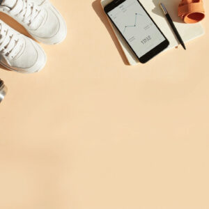 Flatlay d’objets liés au sport et à la stagnation de la perte de poids : baskets, gourde, mètre ruban, smartphone de suivi et carnet
